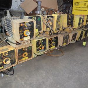 A bunch of old style welding machines sitting on top of cardboard.