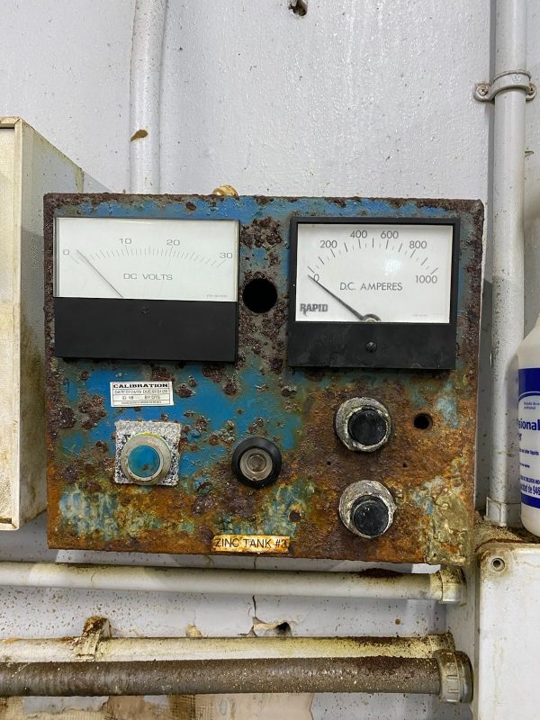 A rusty old meter on the side of a building.