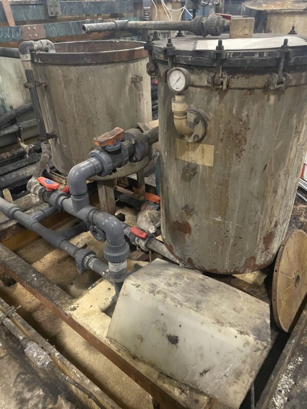 A dirty tank with pipes and valves on it.