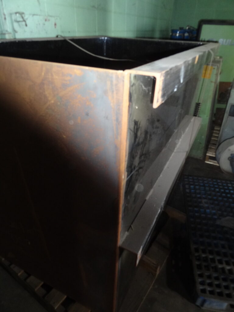 Large rusty industrial metal tank with open top