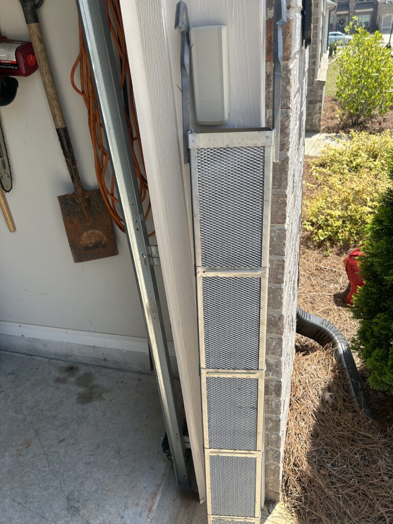 Vertical metal mesh vent along garage doorway
